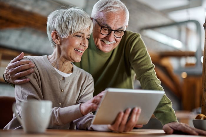 Two smiling people looking at a tablet together.