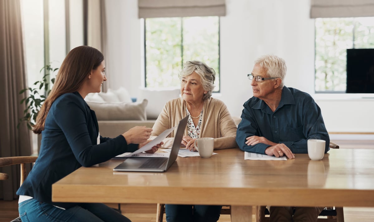 Three people have a conversation at a table.
