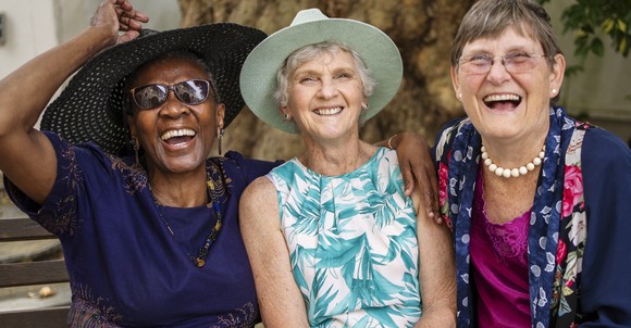 Three people sitting side by side and smiling.