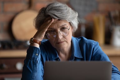 Retiree staring at computer in distress