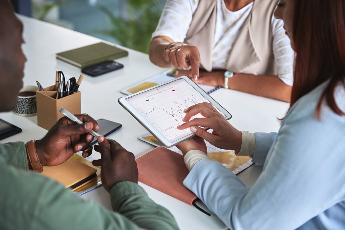 A team of employees sitting around a table in an office using software to collaborate.