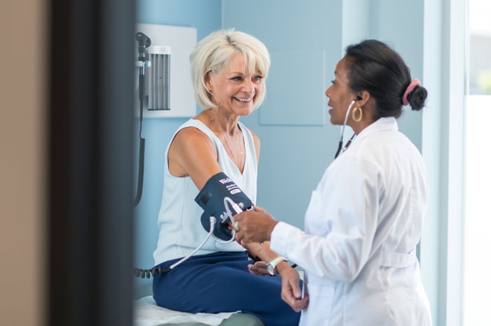 Smiling person having their blood pressure checked.