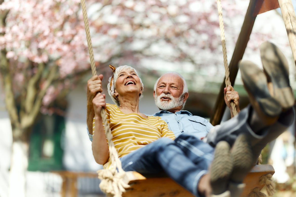 Two smiling people on a swing.