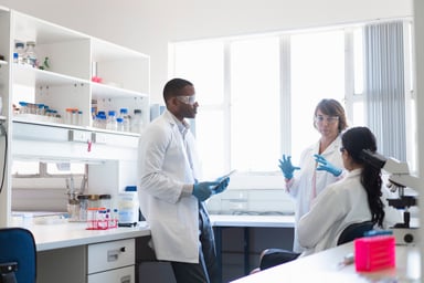 three scientists chat at a lab bay