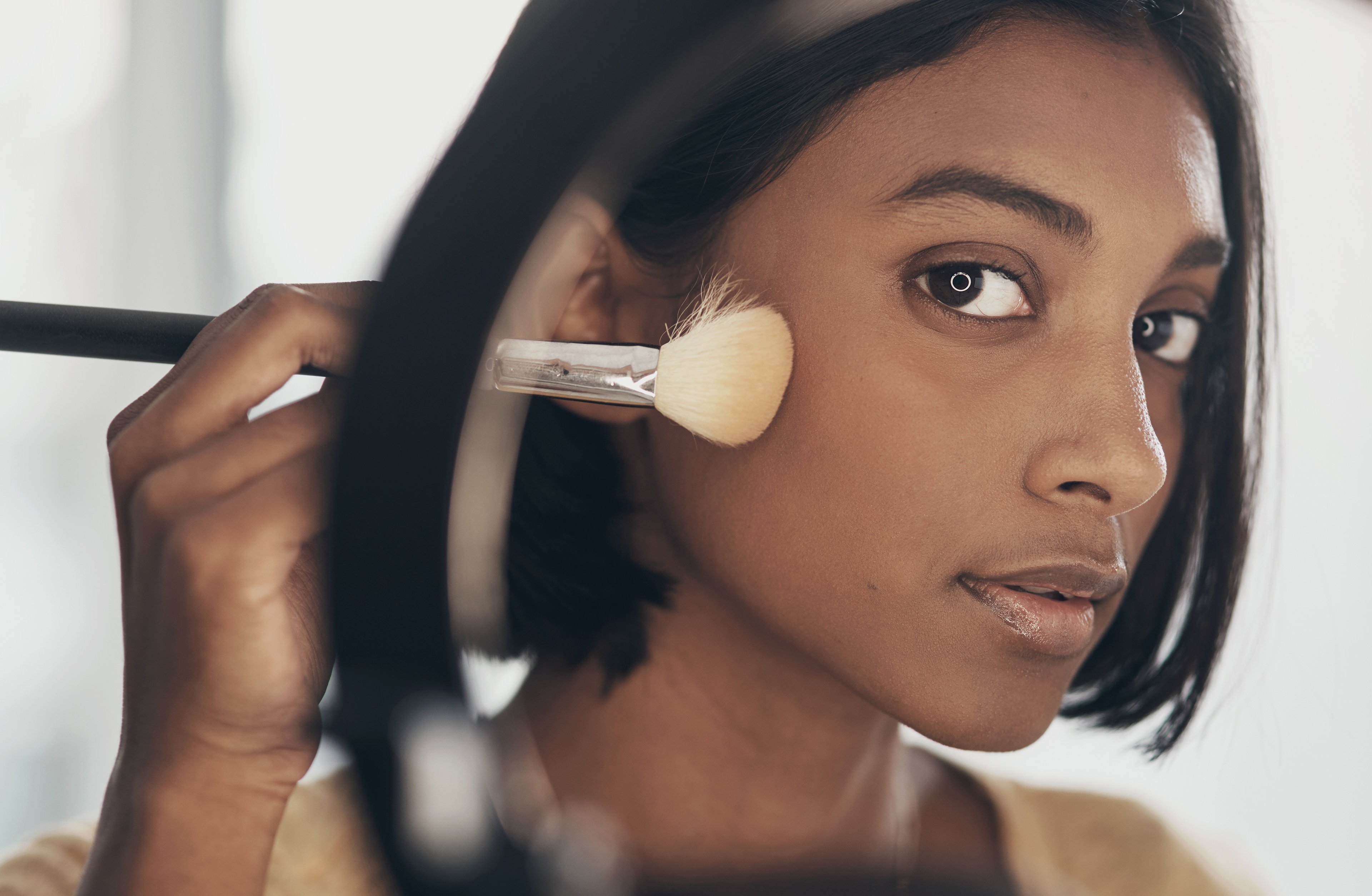 Closeup of young woman putting on makeup. 