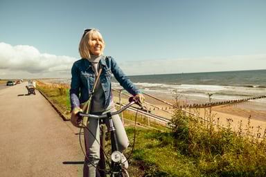 Smiling person riding on bicycle by the ocean