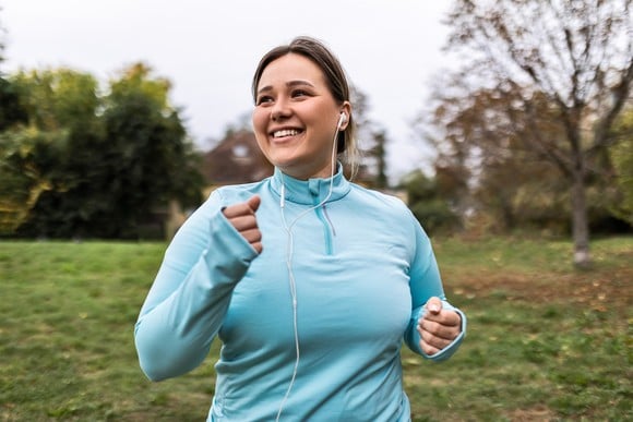 A person smiling while listening to headphones and wearing athleisure attire. 