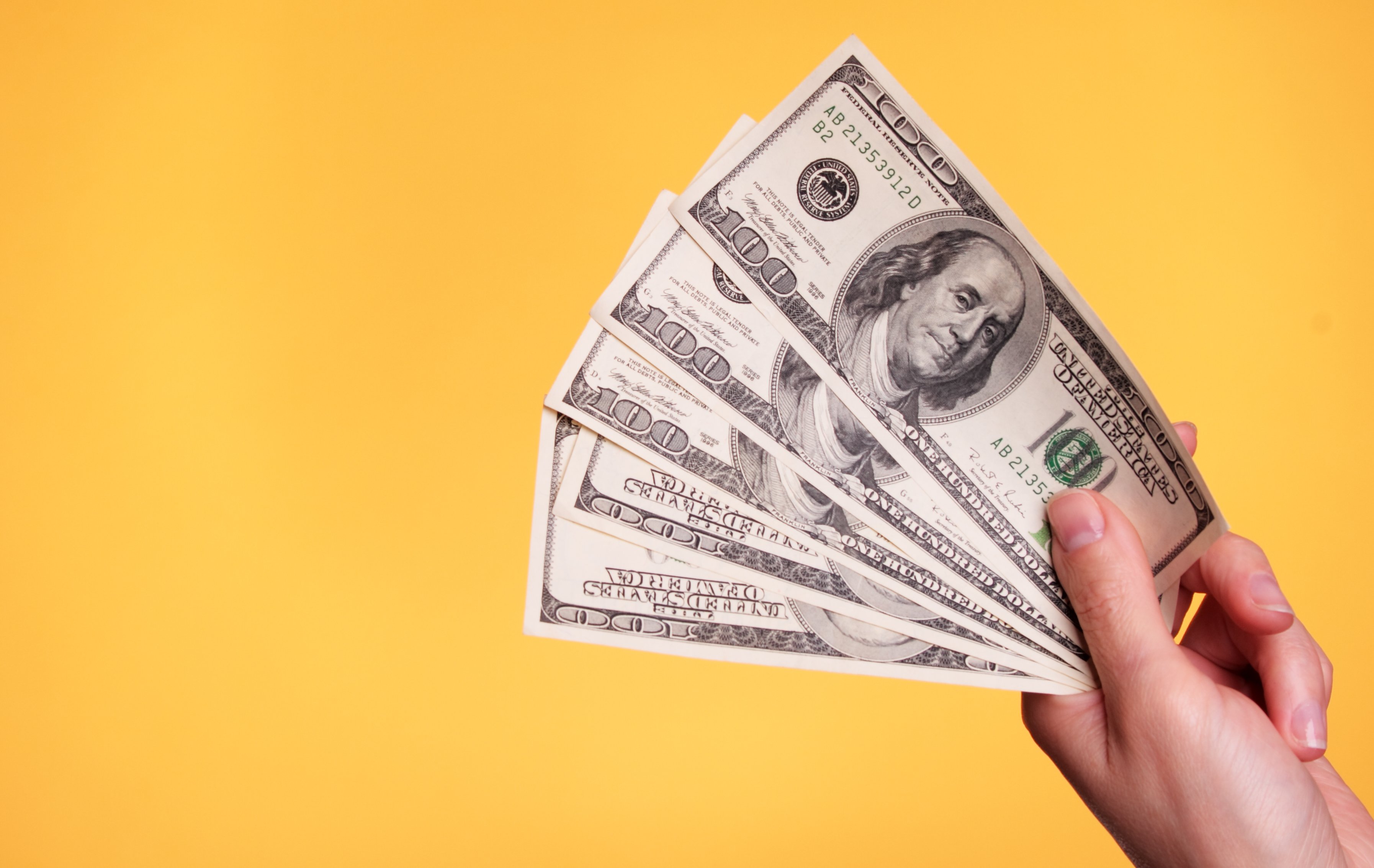 person holding hundred dollar bills copy