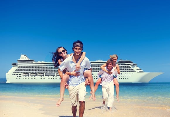 Friends walk up the shore with a cruise ship in the background.
