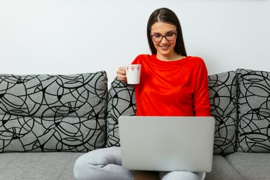 Smiling person with cup looking at laptop