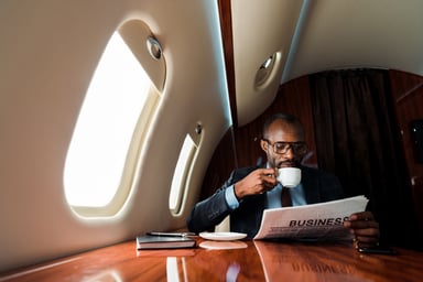 Person reading a newspaper on a private jet.