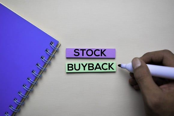 A spiral notebook, a marker, and the words Stock and Buyback written on two colored labels.