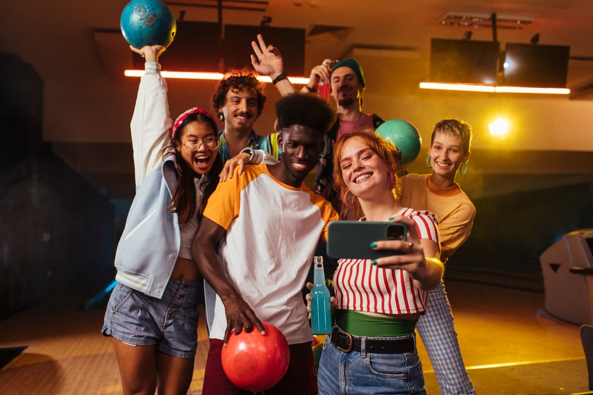 Group of people with vibrant facial expressions facing a handheld mobile device.
