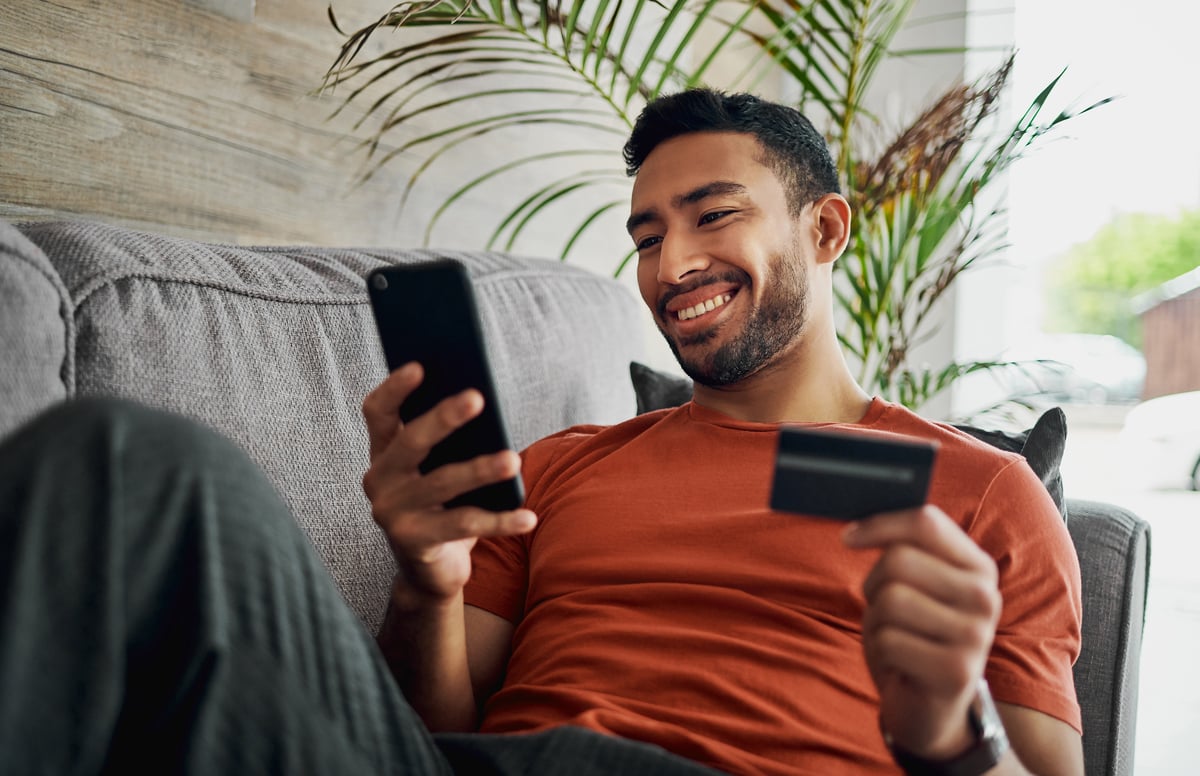 A person holding a credit card and a mobile phone