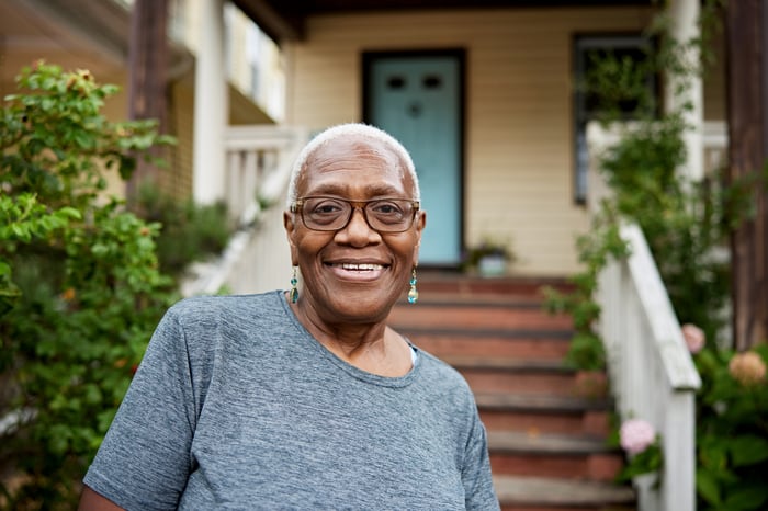 Someone is smiling outside the porch of a house.