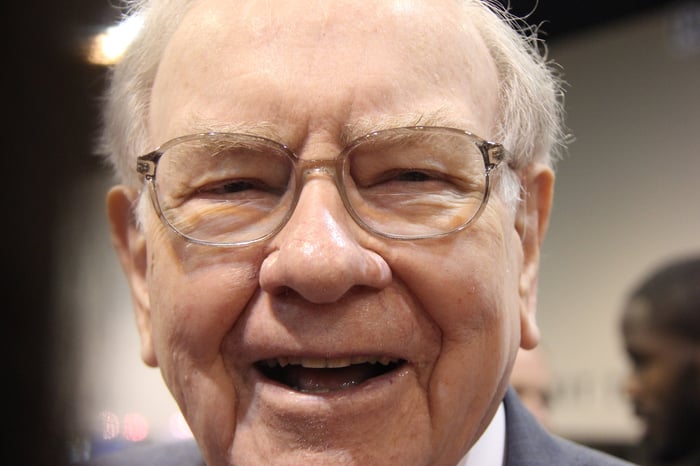 A jovial Warren Buffett surrounded by people at Berkshire Hathaway's annual meeting.