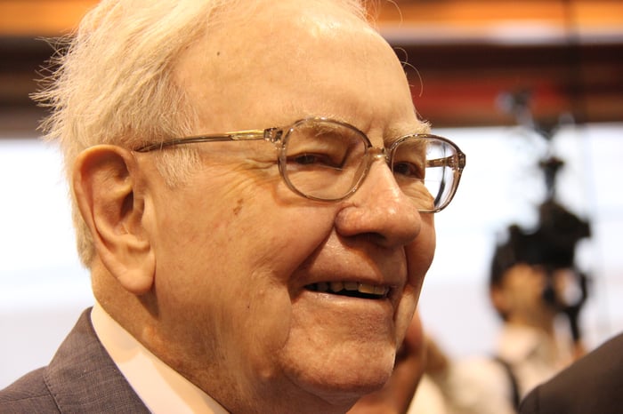 A smiling Warren Buffett surrounded by people at Berkshire Hathaway's annual shareholder meeting.