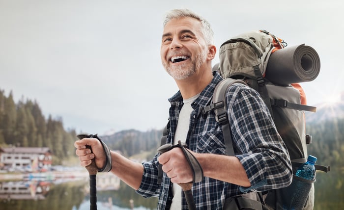 Smiling person hiking by a lake.