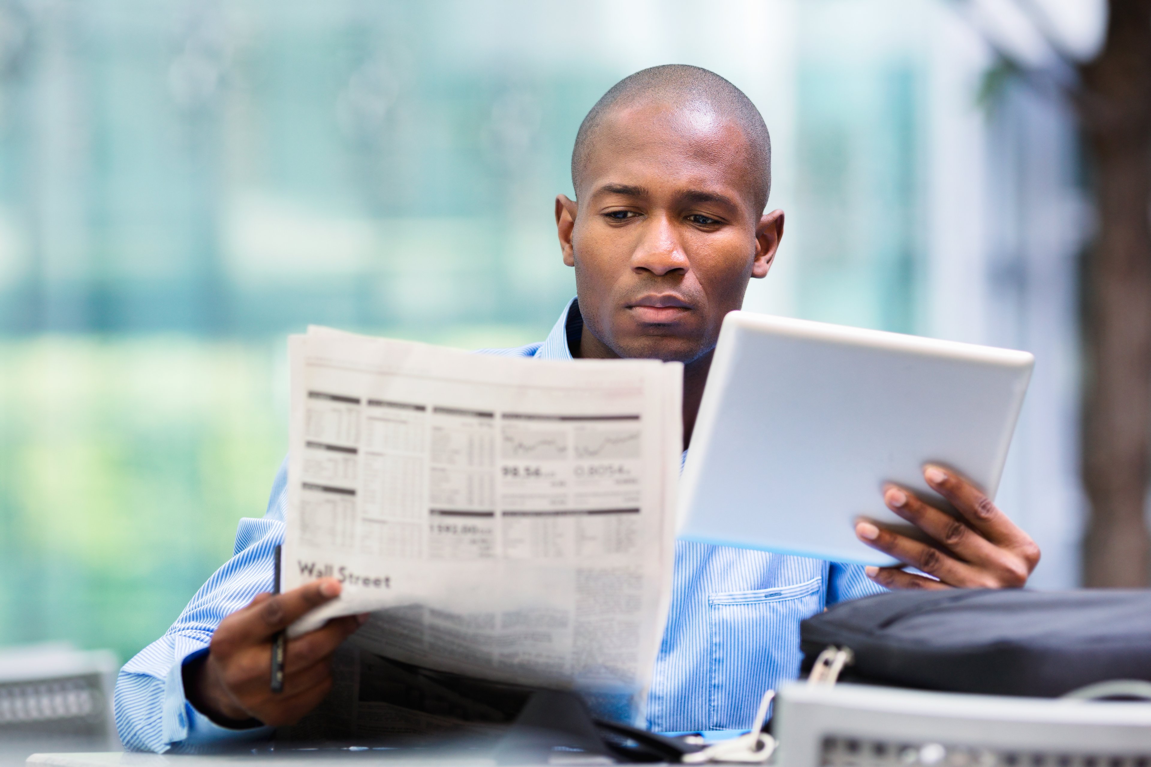 a person reviews a tablet and a newspaper getty