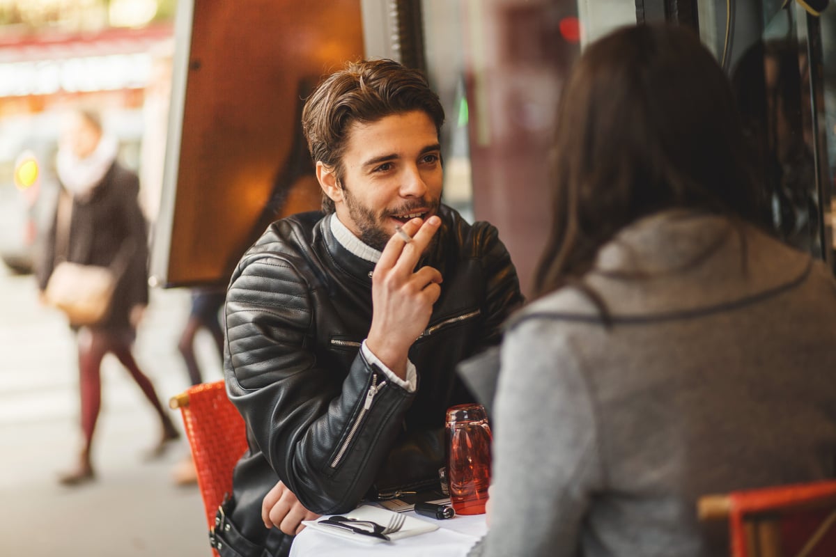 Person seated at a table in an outdoor cafe.