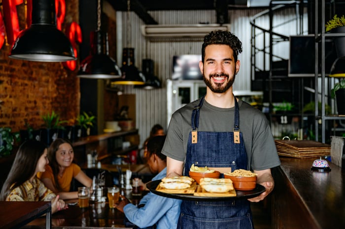 Person holding a tray of food within a restaurant setting.