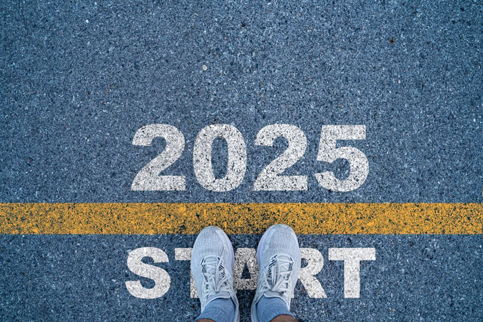 2025 is written on a starting line for a race with a focus on a person's feet in sneakers.