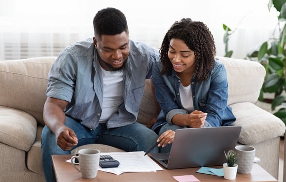 Two people on couch, looking at documents together.