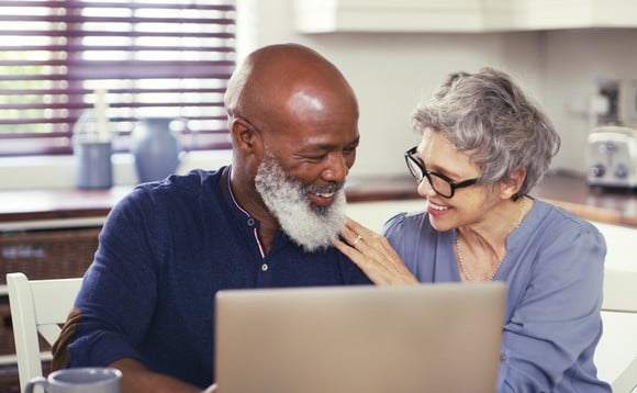 Two people looking at laptop in kitchen.