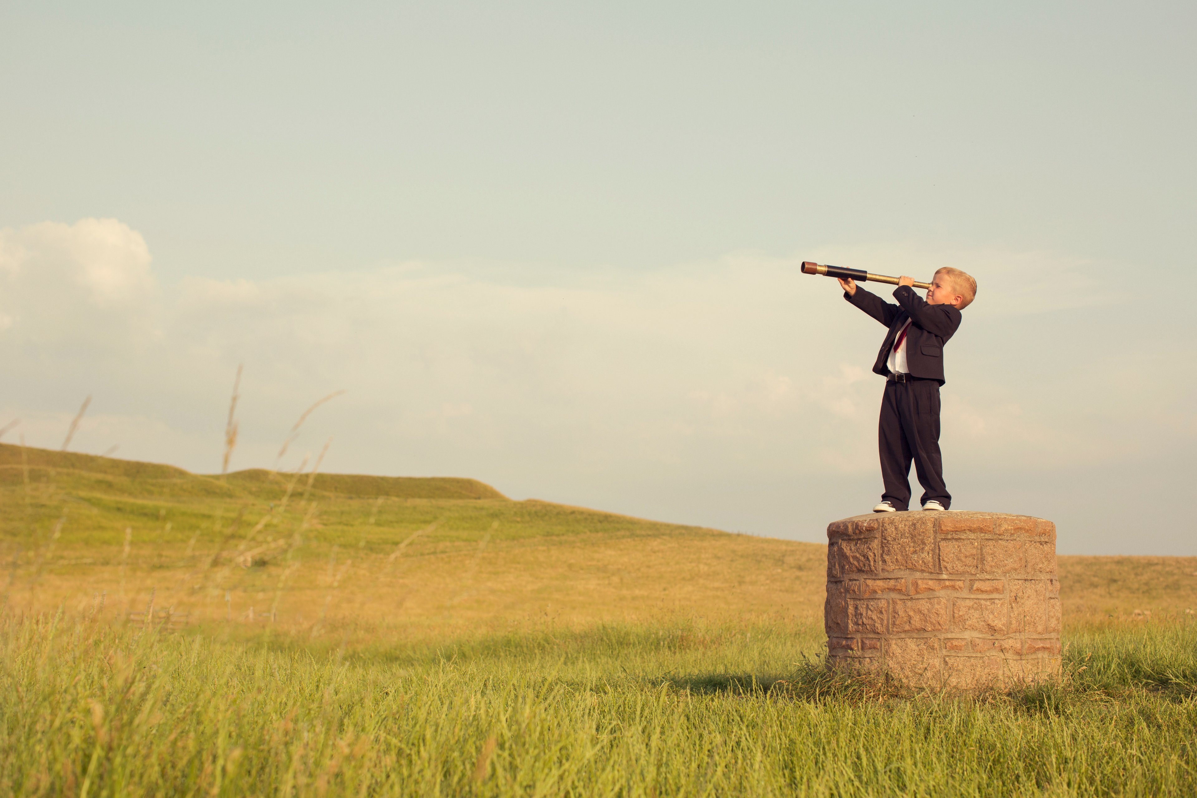A child looking into the distance through a telescope.