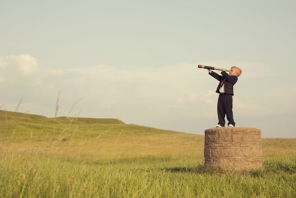 A child looking into the distance through a telescope.