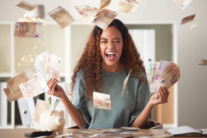 A person celebrating with money raining down on them