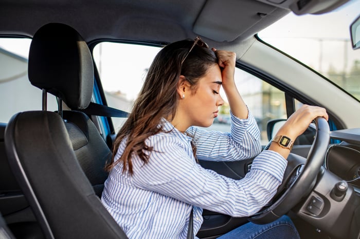 A person who looks stressed while sitting in a car.