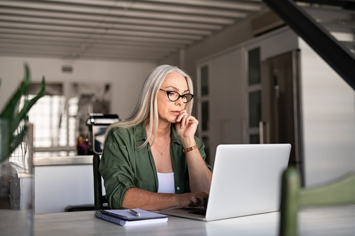 Person staring intently at laptop with hand on chin.