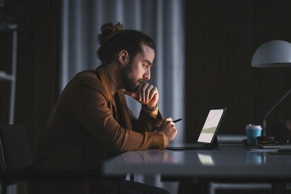 An investor looks at something on a tablet in a darkened office.