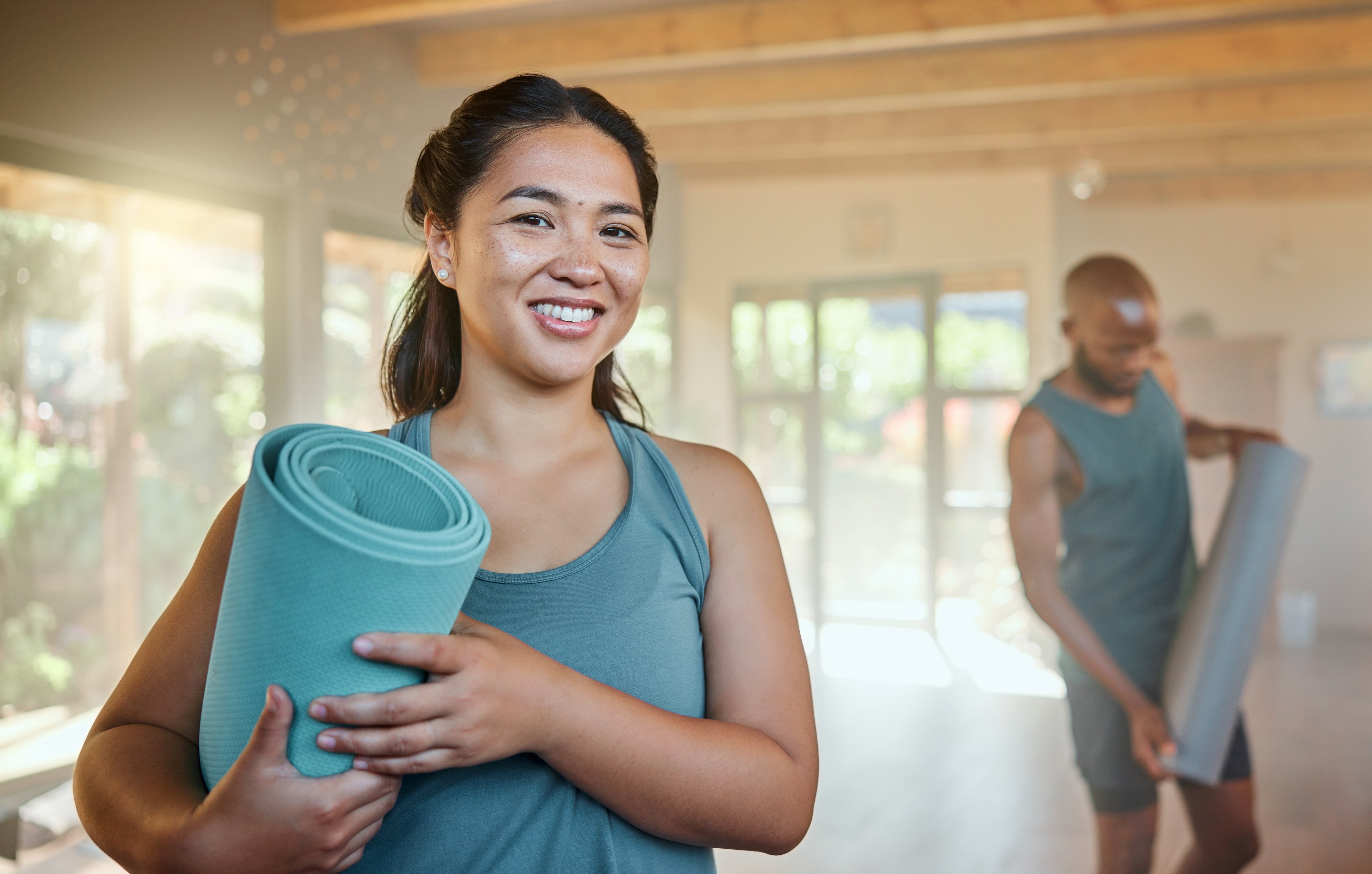 People holding yoga mats in studio.