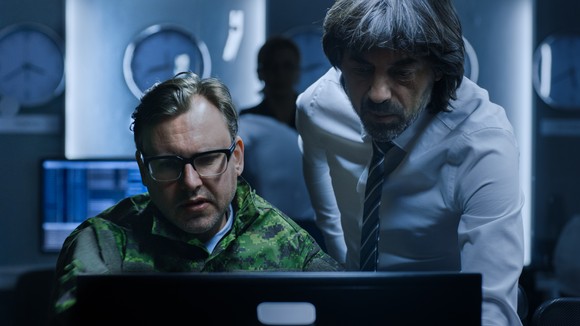 Two agents in a dark room looking at a computer room