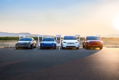 Tesla models at chargers with setting sun