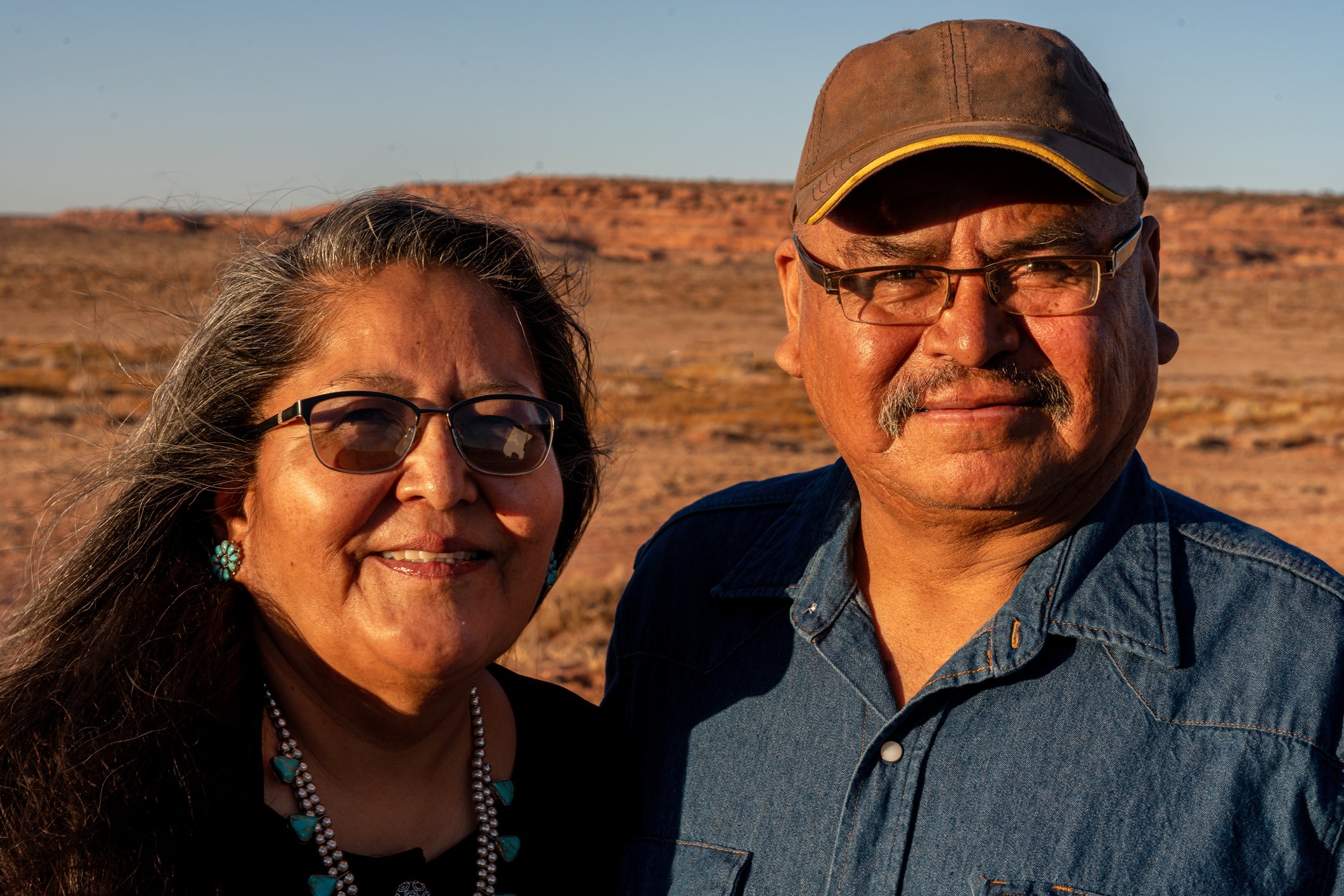Two people standing outside in a desert, with slight smiles.