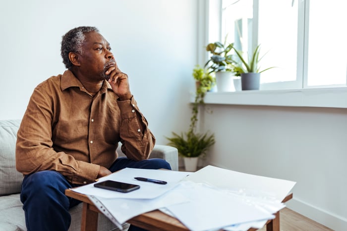 A person sitting on a couch with documents spread out on a coffee table.