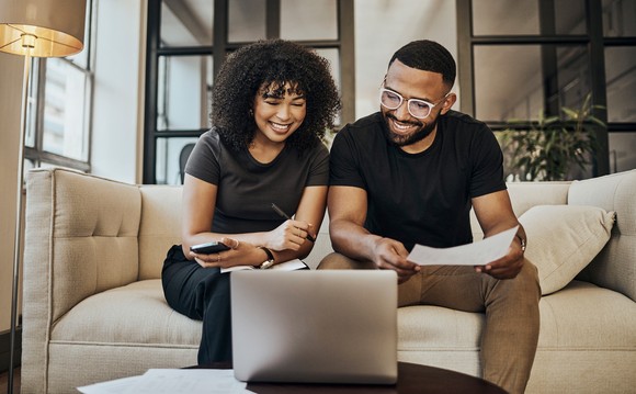 Two people sitting on a couch and looking at a laptop.
