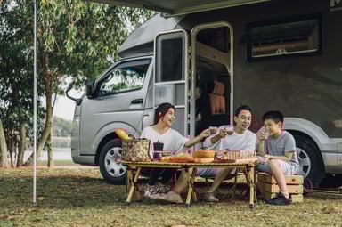 A group of people camping in front of an RV