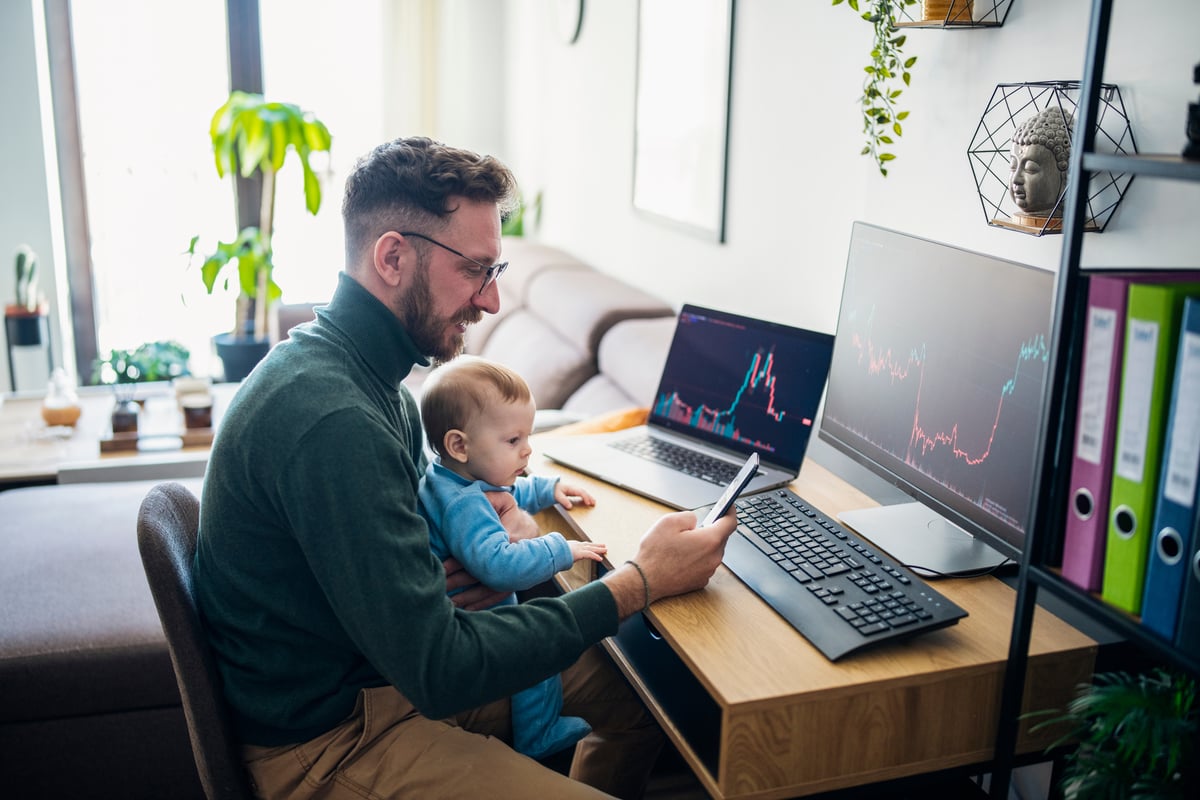 A person sitting at a computer holding a baby