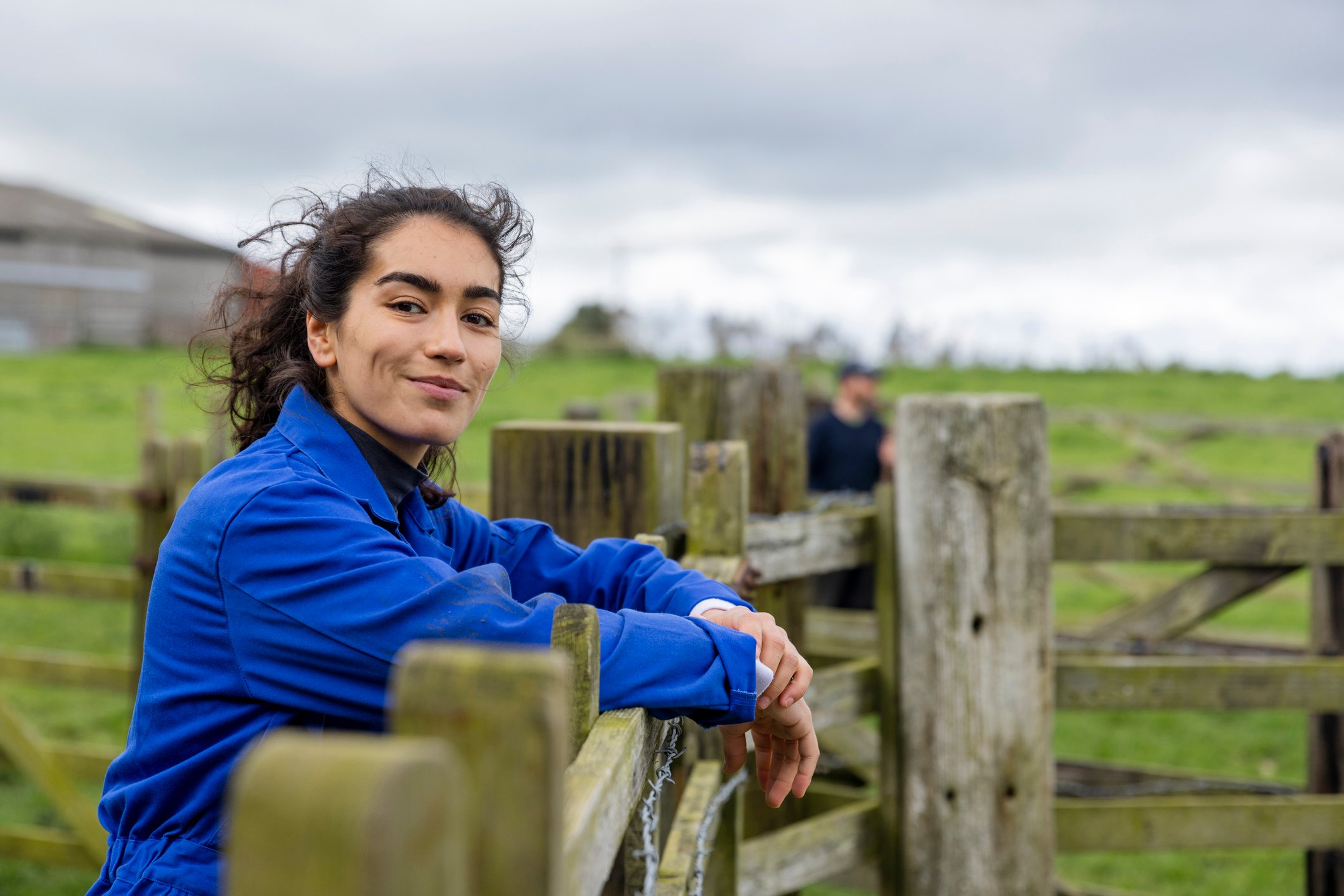 Someone is leaning on a fence and smiling.