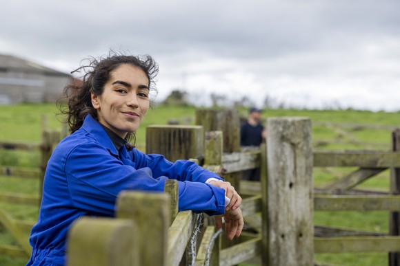 Someone is leaning on a fence and smiling.