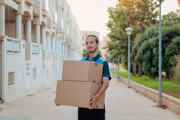 A delivery person holding two cardboard boxes.