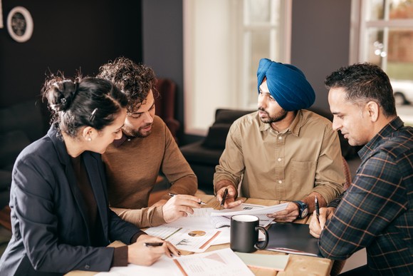 A group of people sitting at a table, discussing papers.