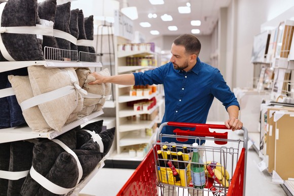 Person holding a red shopping cart within a retail environment.