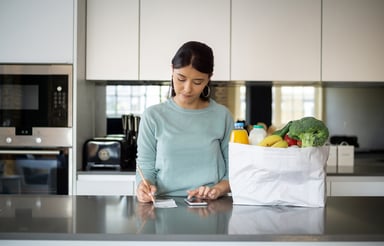 Person in a kitchen with a bag of groceries
