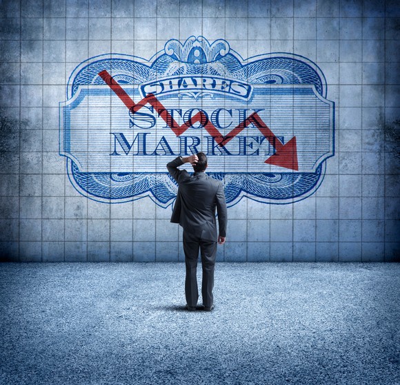 An investor looks at a sign that shows a down arrow over the words "stock market."