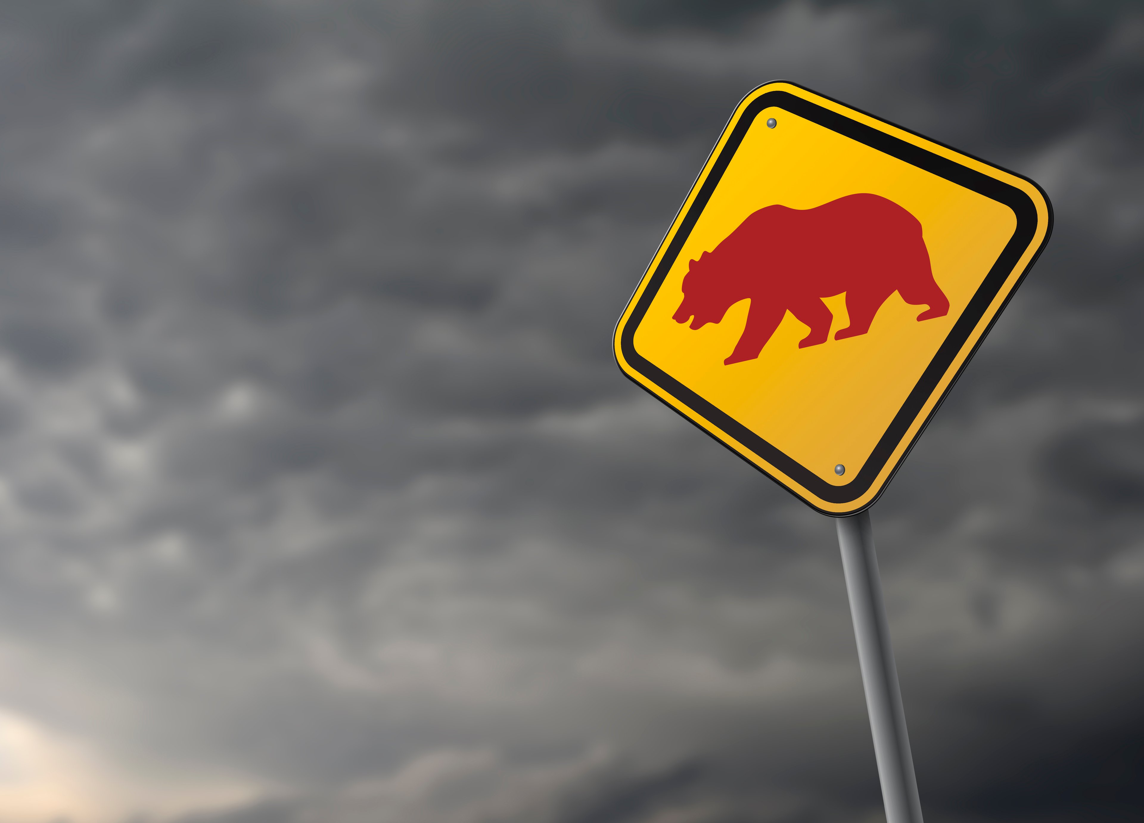 Sign with bear against a stormy sky.